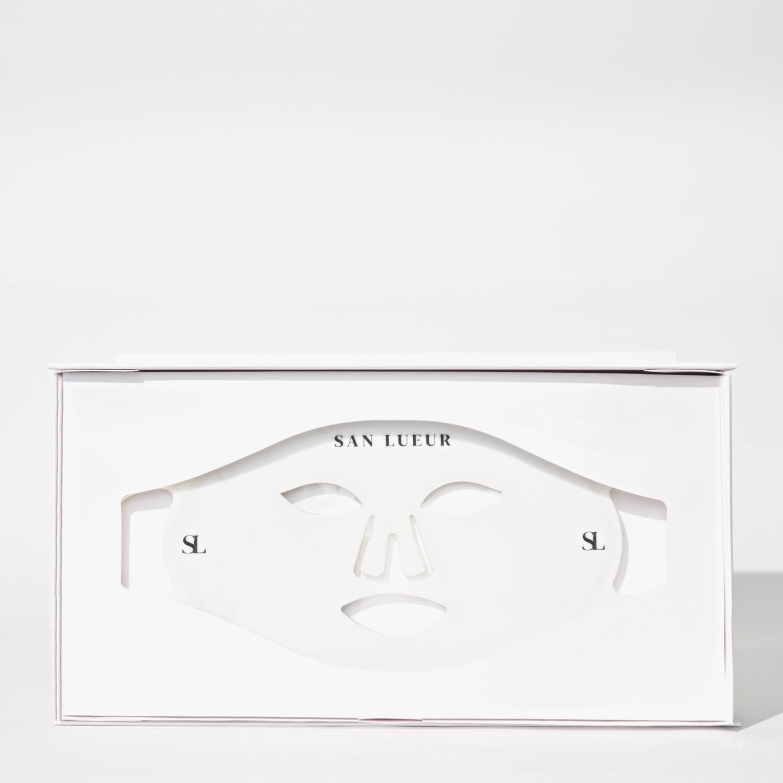 A white SAN LUEUR skincare mask box with a die-cut face mask visible through the front window, photographed on a clean white background.