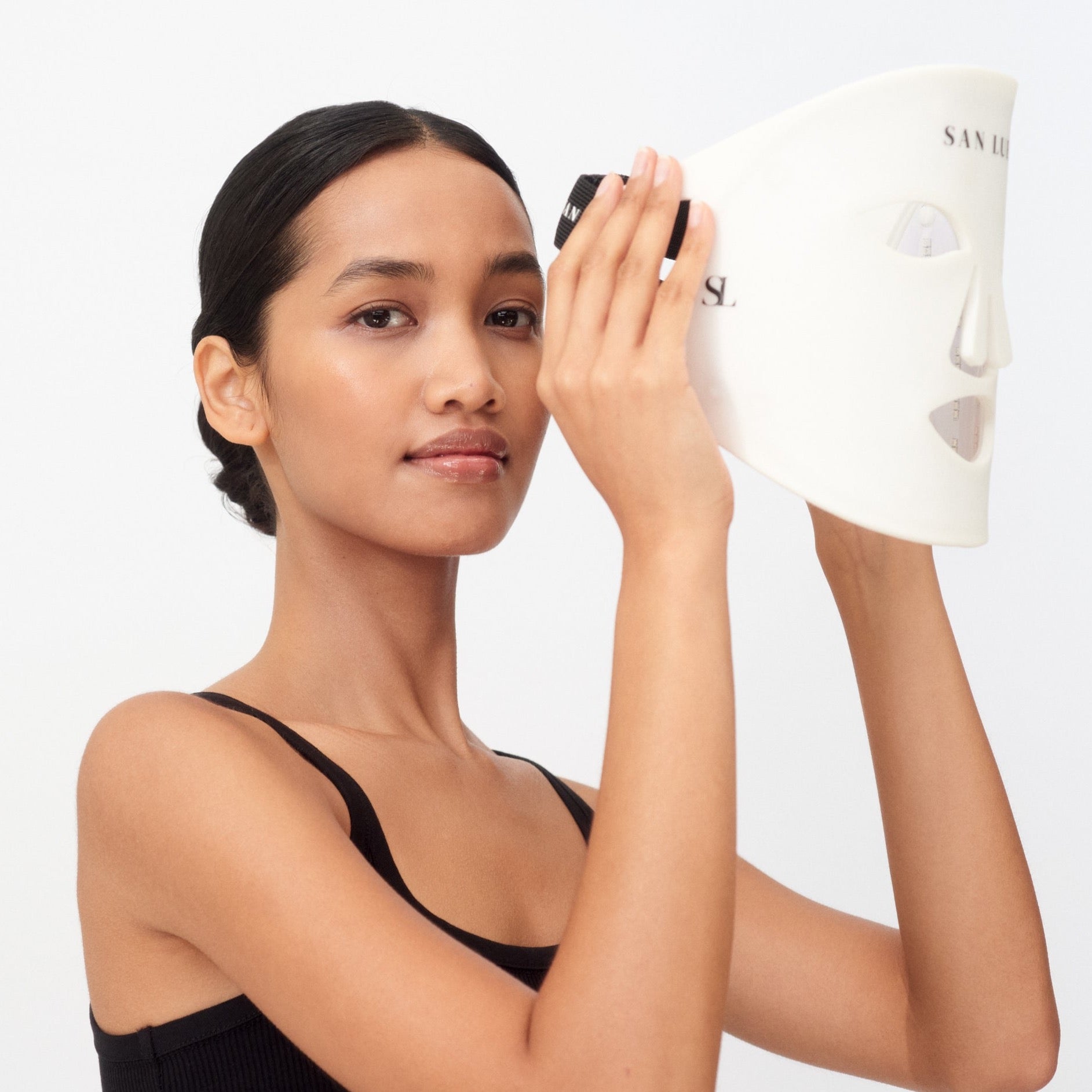 Woman holding a skincare product with a plain background