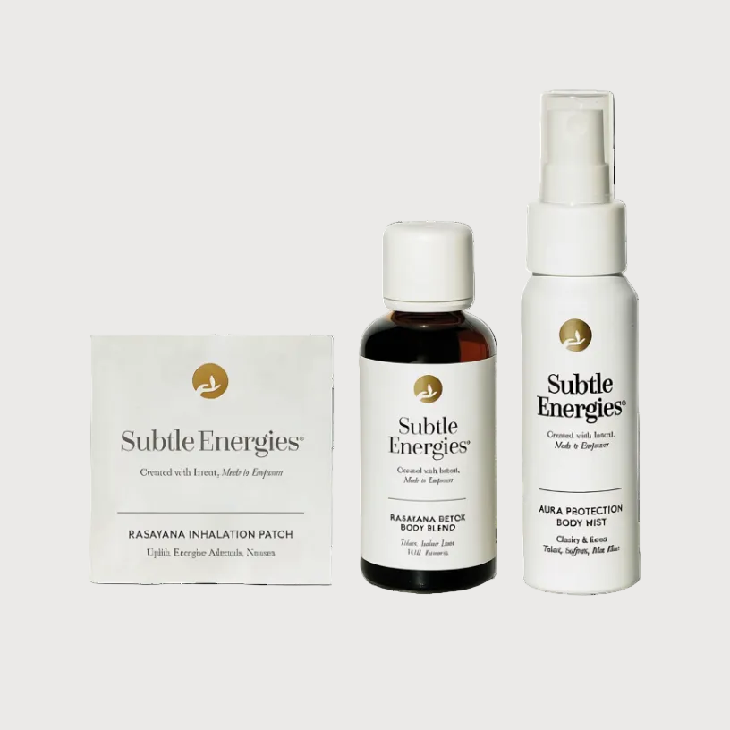 Three skincare products from Subtle Energies arranged on a white background: a square cream-colored patch box, a small amber bottle with a white cap, and a white spray bottle with a clear nozzle. The labels read Subtle Energies, Ramana Setek Body Alchemy, and Aba Protection Body Wash.