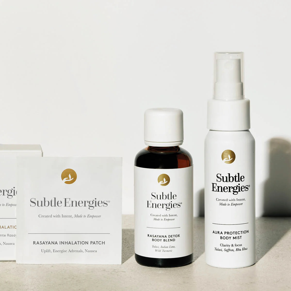 Collection of Subtle Energies products including a spray bottle, a bottle, and a box on a neutral background.