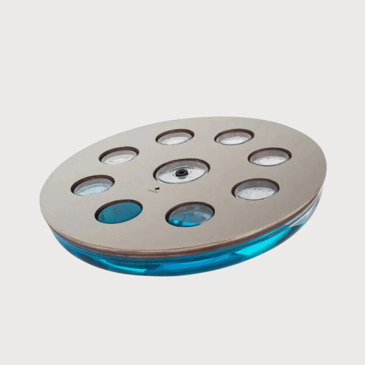 Round metallic object with blue glass insert on a white background