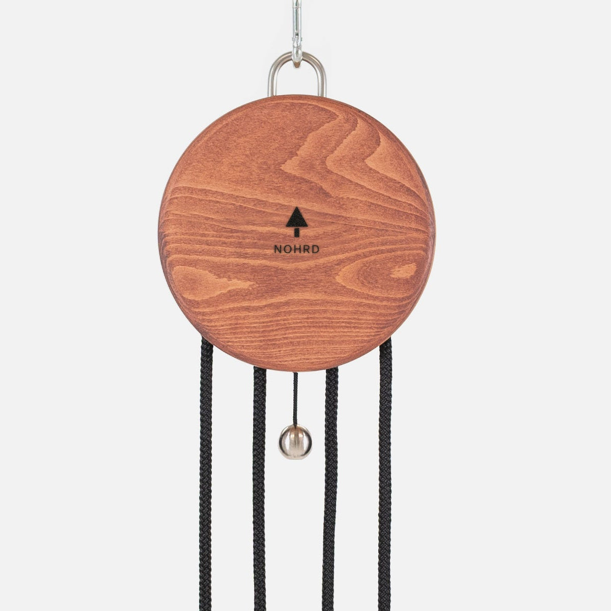 A wooden hanging wind chime with a round reddish-brown wood disc, black cords, and a small silver bell, shown against a plain light gray background.