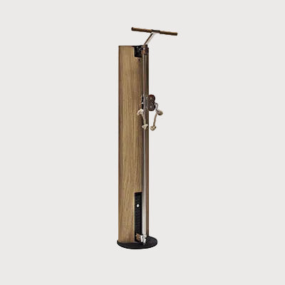 A modern freestanding pump station with a tall rectangular wood-grain cabinet, a black base, and a brass T-bar handle on top, set against a plain light gray background.