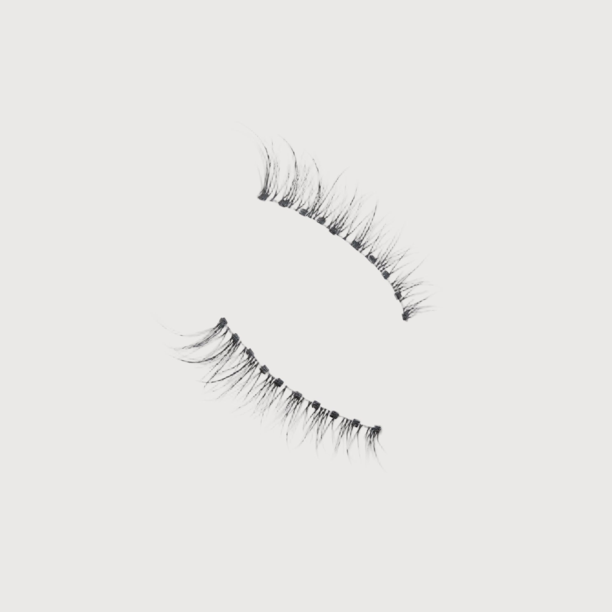 Pair of false eyelashes on a light gray background