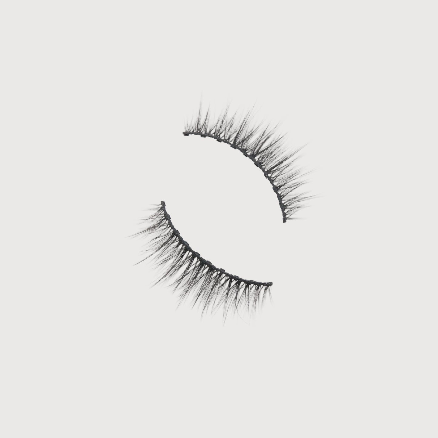 Pair of false eyelashes on a light gray background