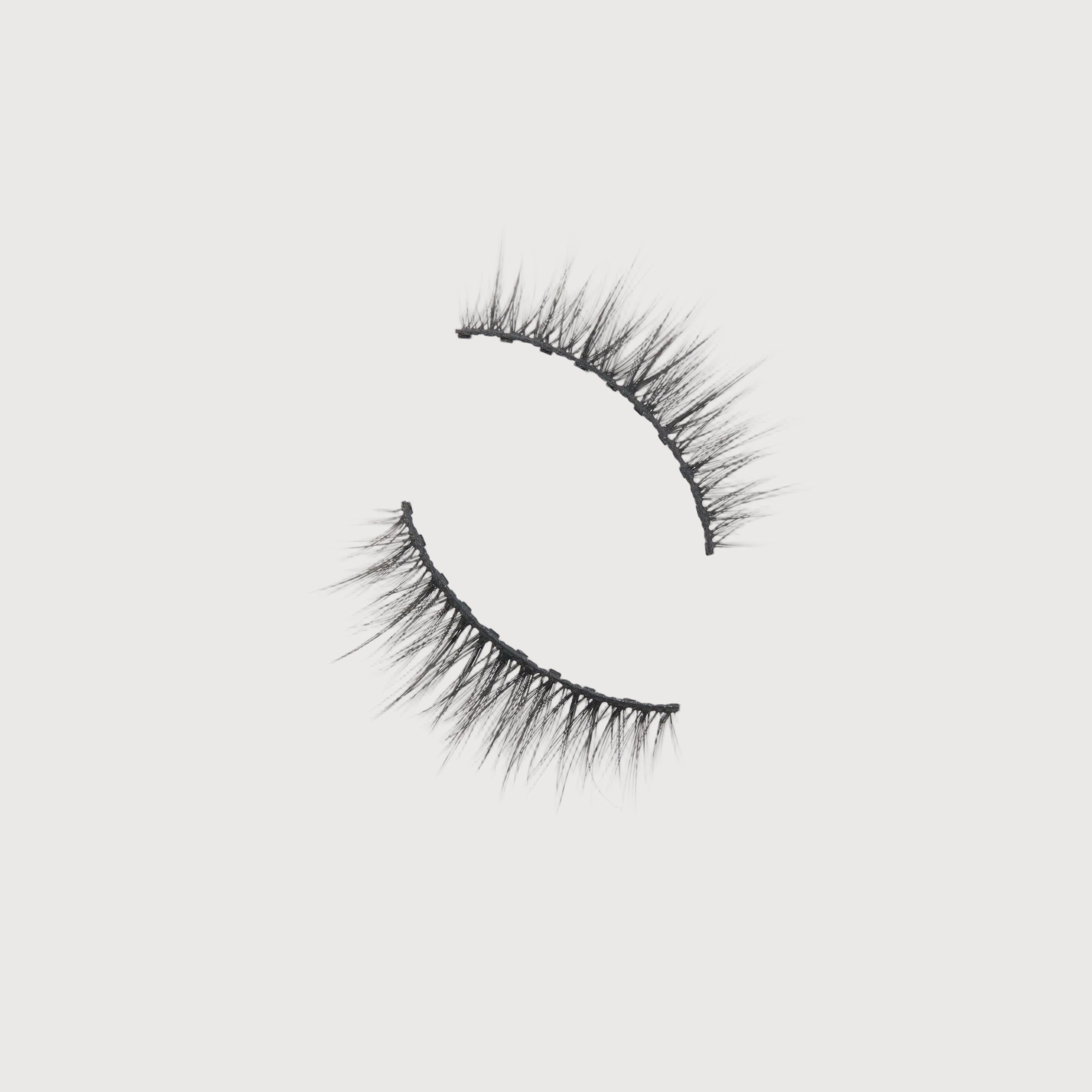 Pair of false eyelashes on a light gray background