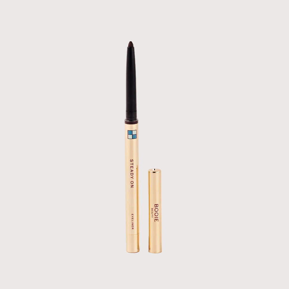 Two makeup products, a eyeliner pencil and a concealer stick, on a light pink background.