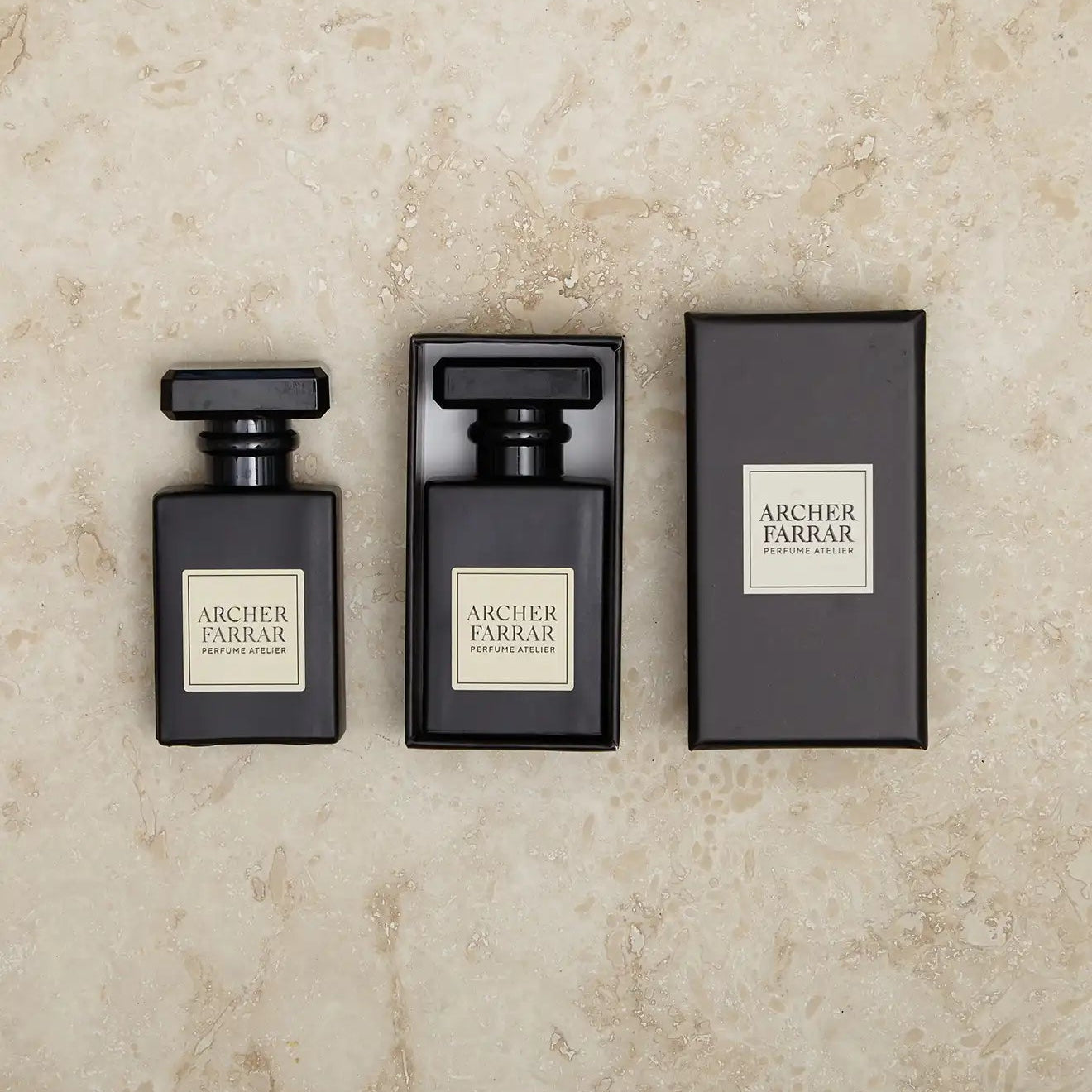 Three black perfume bottles with 'Archer Farrar' labels on a beige marble background