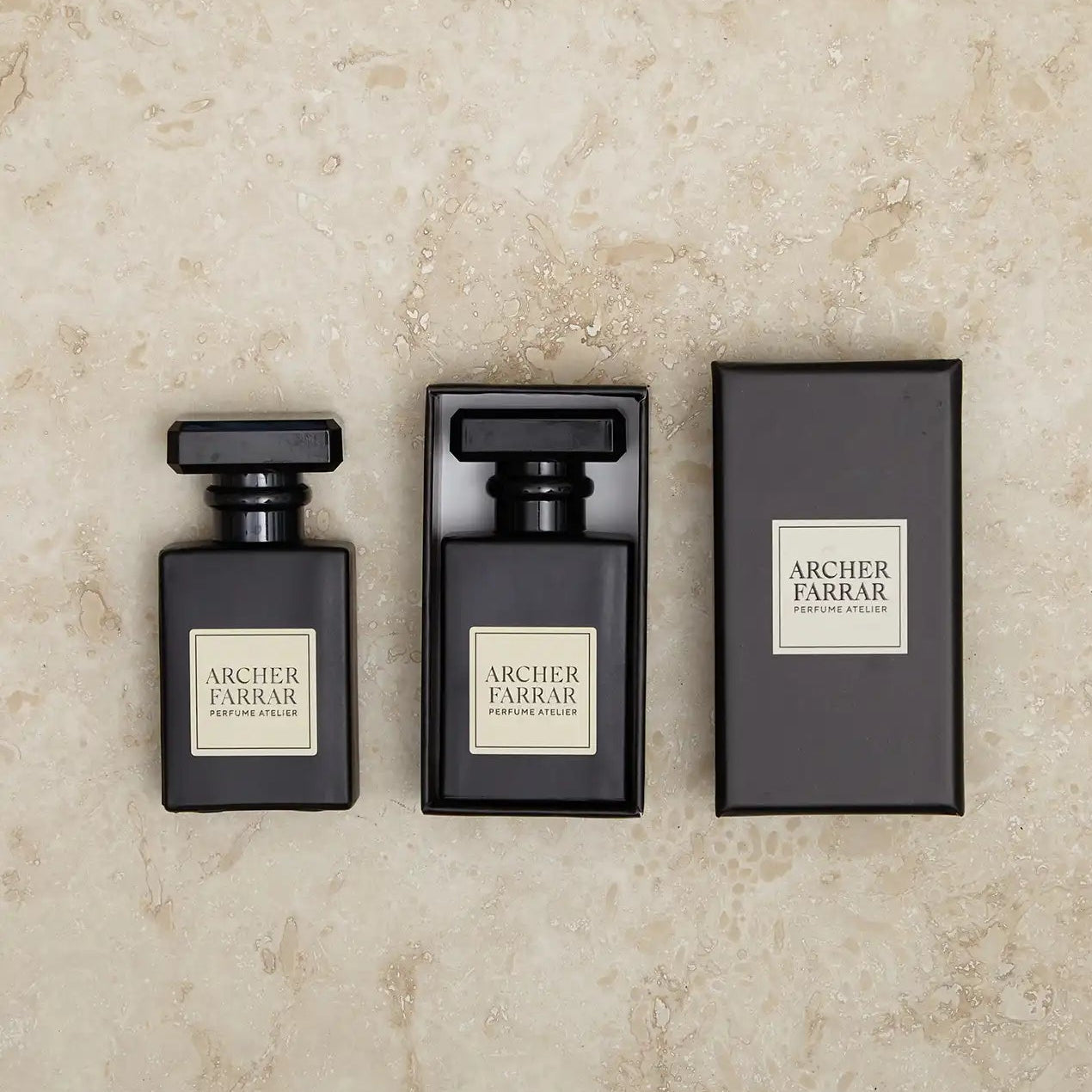 Three black perfume bottles with 'Archer Farrar' labels on a beige marble background