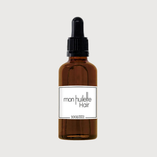 Brown glass bottle with black dropper labeled 'mon huilette Hair' on a white background