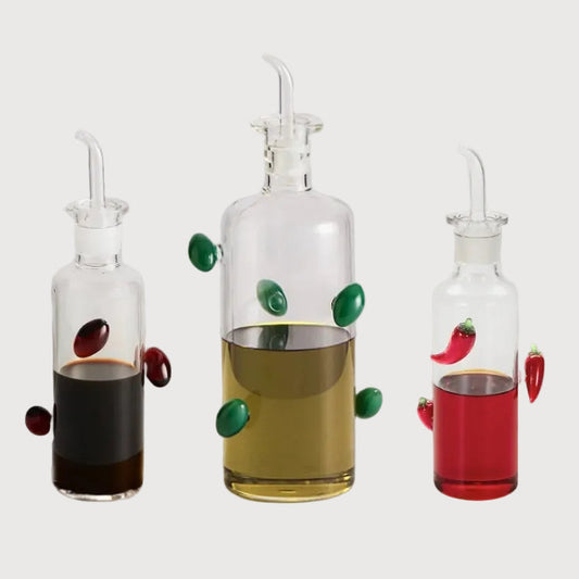 Three glass oil dispensers with colorful accents on a white background