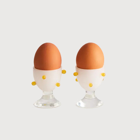 Two brown eggs in clear egg holders on a white background