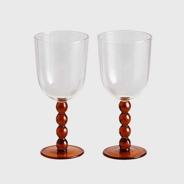 Two clear wine glasses with wooden bases on a white background