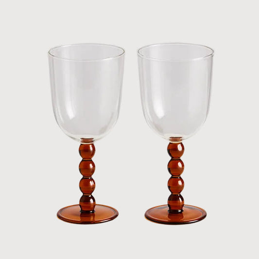 Two clear wine glasses with wooden bases on a white background