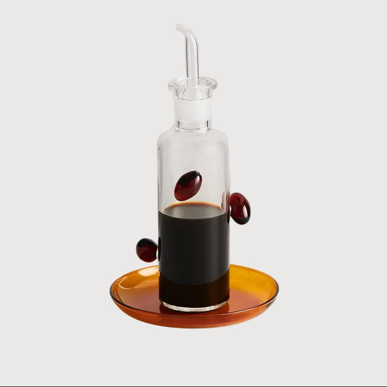 Clear glass bottle with a dropper on an orange dish against a white background