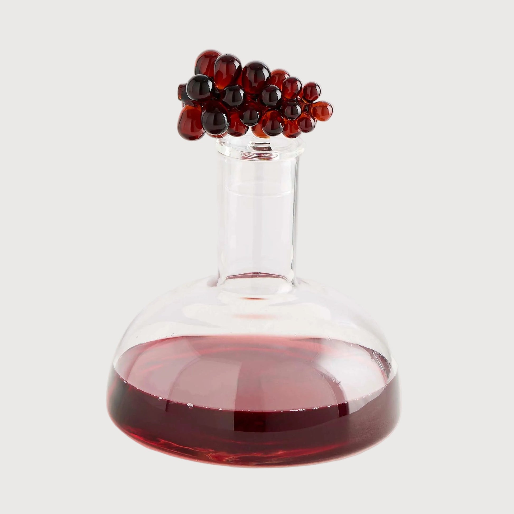 Glass container with red liquid and black beads on a white background