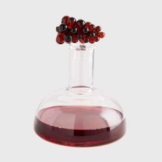 Glass container with red liquid and black beads on a white background