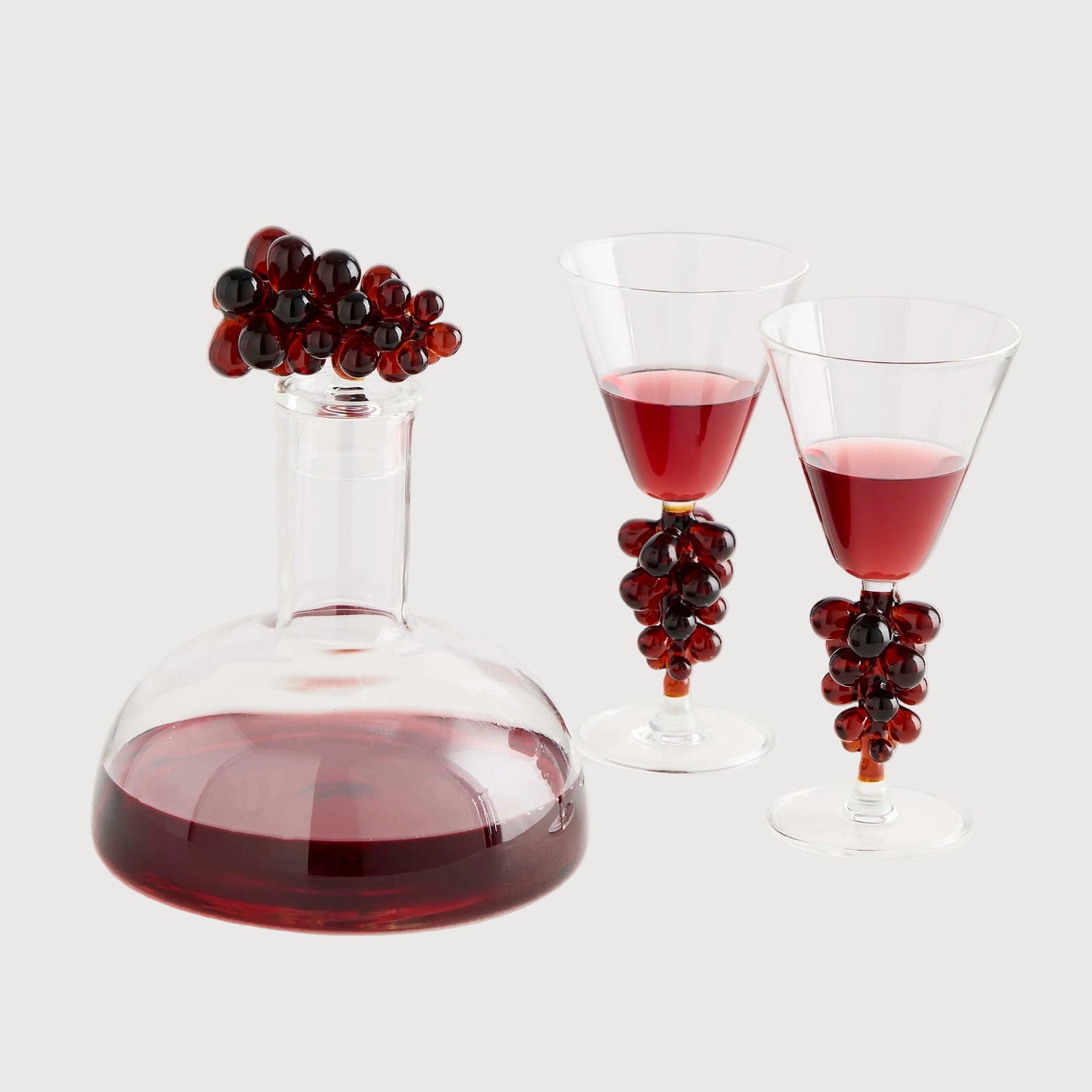 Wine decanter and glasses with red wine and decorative grapes on a white background