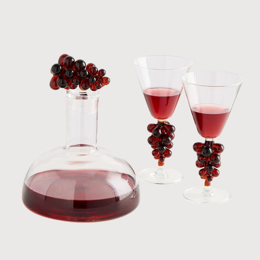 Wine decanter and glasses with red wine and decorative grapes on a white background