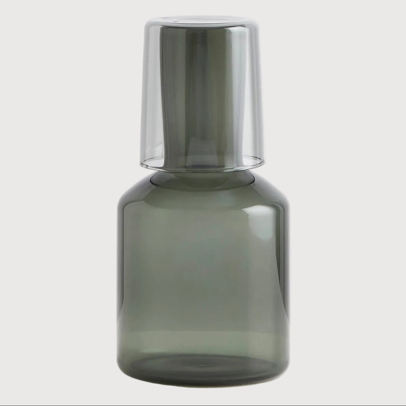 Smoky gray glass bottle with metallic cap on a light gray background