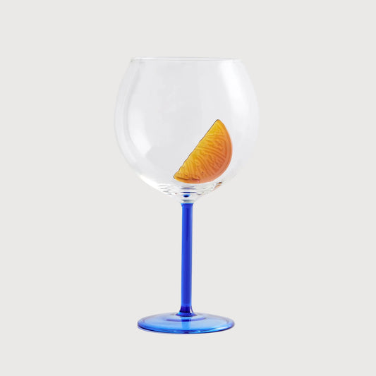 Clear wine glass with a blue stem and a slice of lemon on a white background