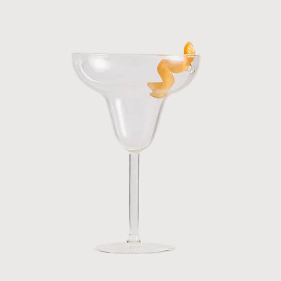Clear martini glass with a small orange object on a white background