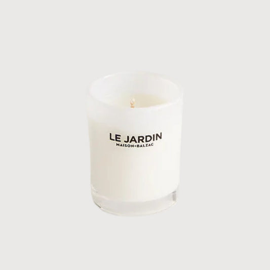White candle with 'Le Jardin' branding on a white background