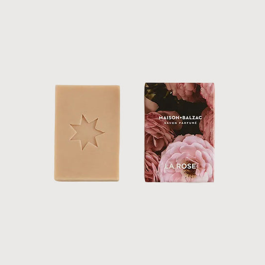 Bar of soap with a star design next to its packaging on a light gray background