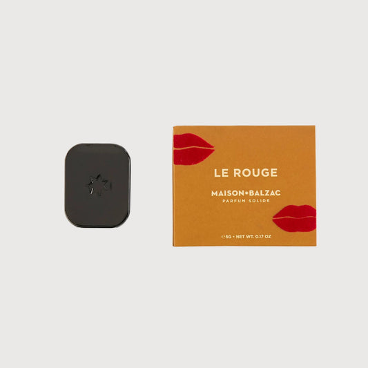 Small black device next to a 'Le Rouge' product box on a white background