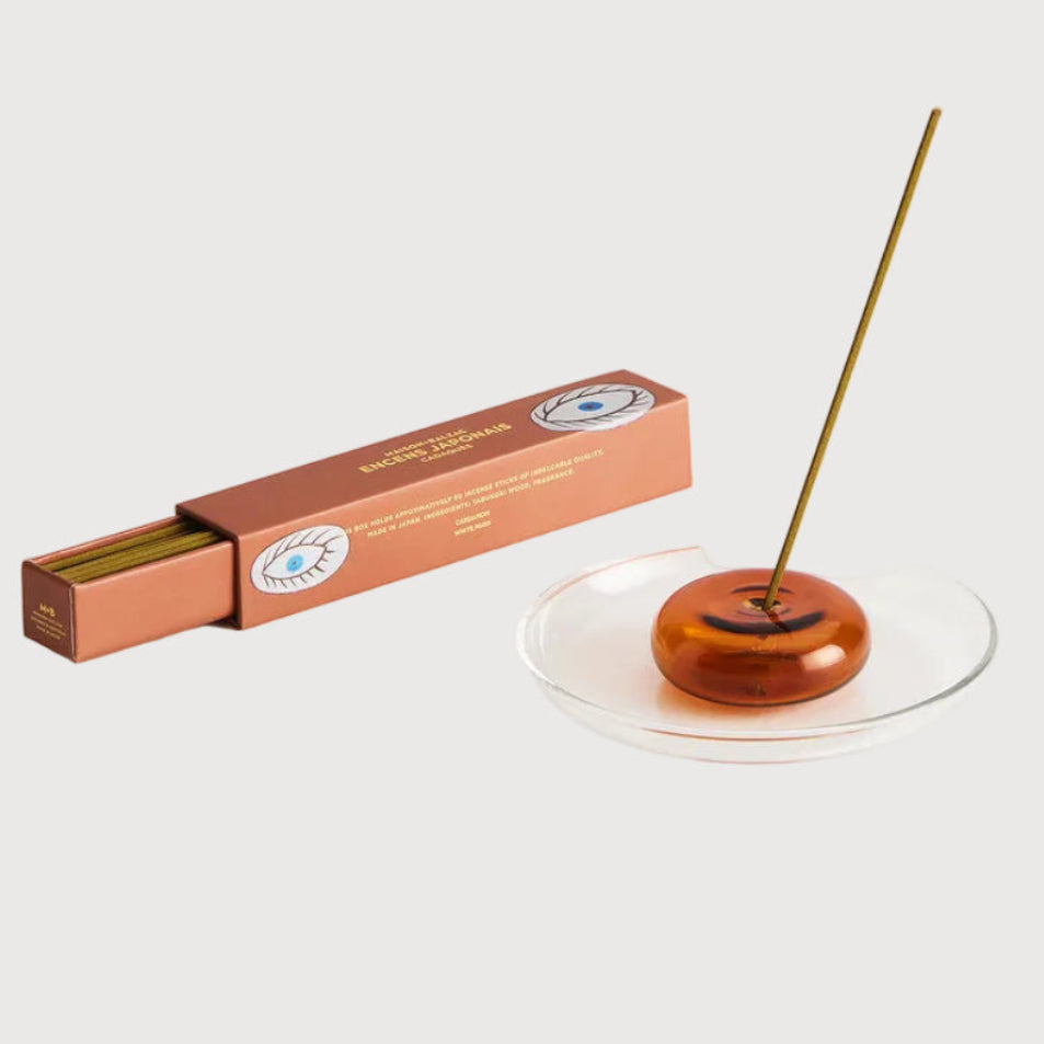 Copper incense holder with a single incense stick and packaging on a white background