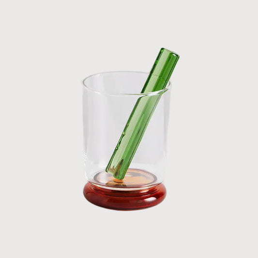 Clear glass with a green pen and red base on a white background