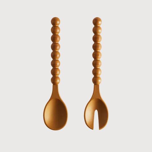 Wooden spoon and fork with textured handles on a light gray background