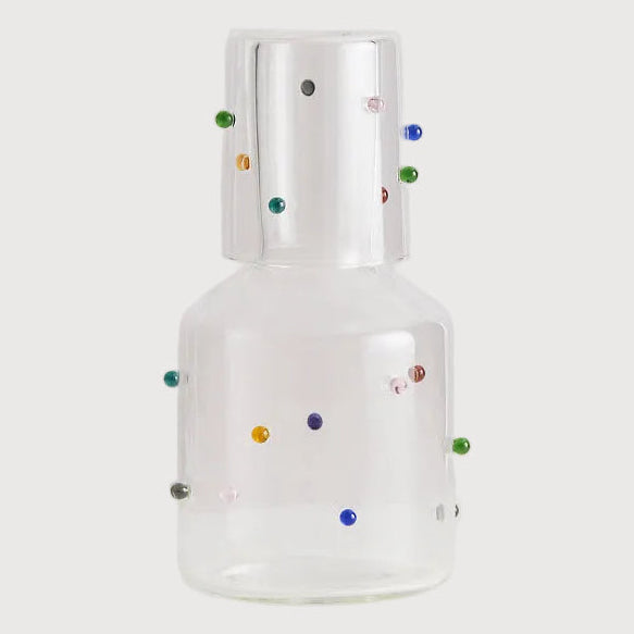 Clear glass bottle with colorful dots on a white background