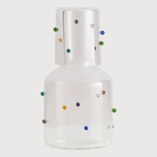Clear glass bottle with colorful dots on a white background