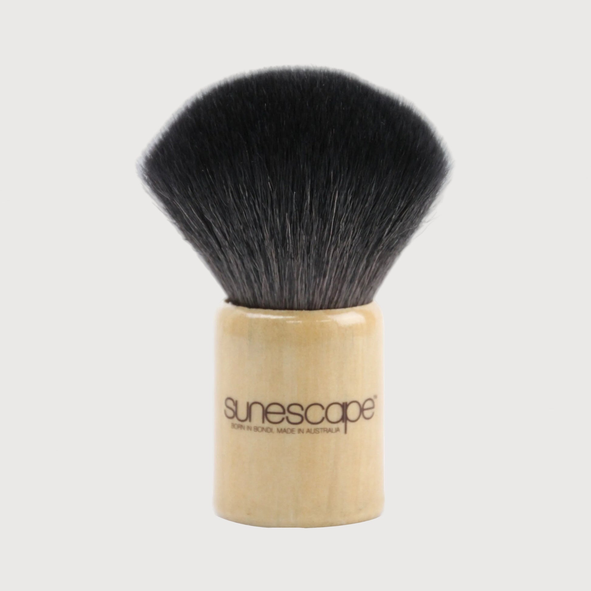 Makeup brush with black bristles and wooden handle on a white background, branded 'sunescapes'.