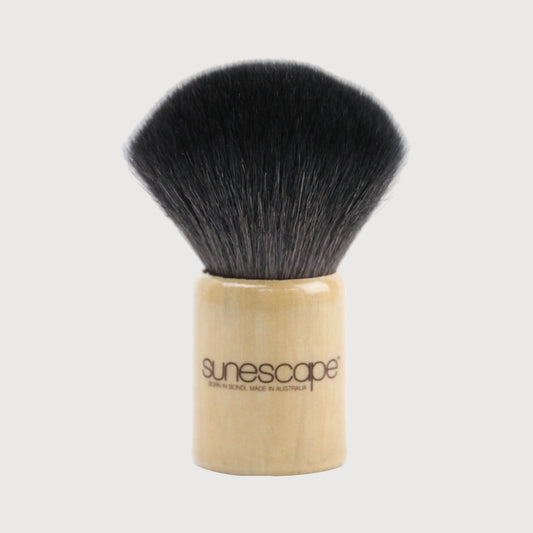 Makeup brush with black bristles and wooden handle on a white background, branded 'sunescapes'.