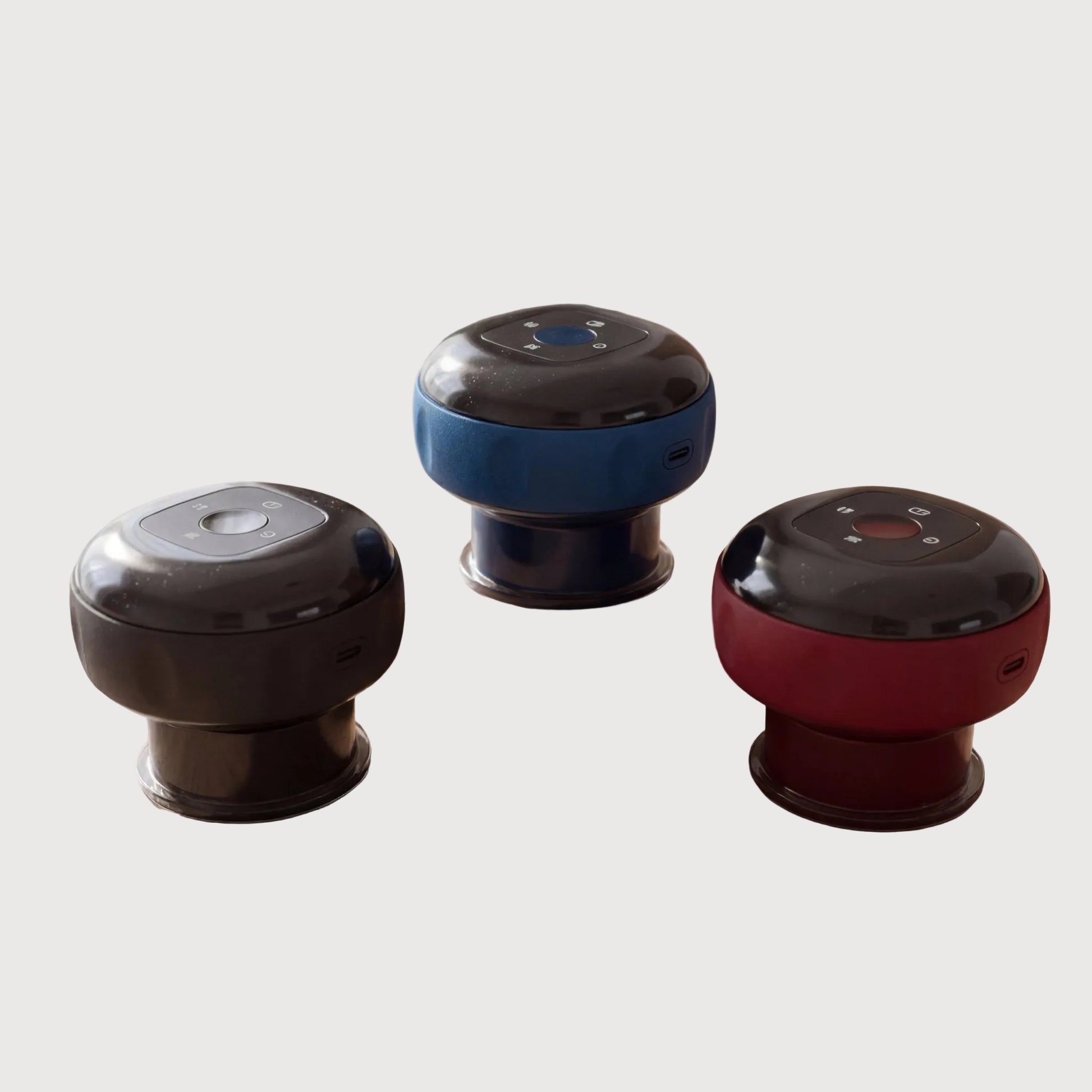 Three small round electronic devices in black, blue, and red on a wooden surface.