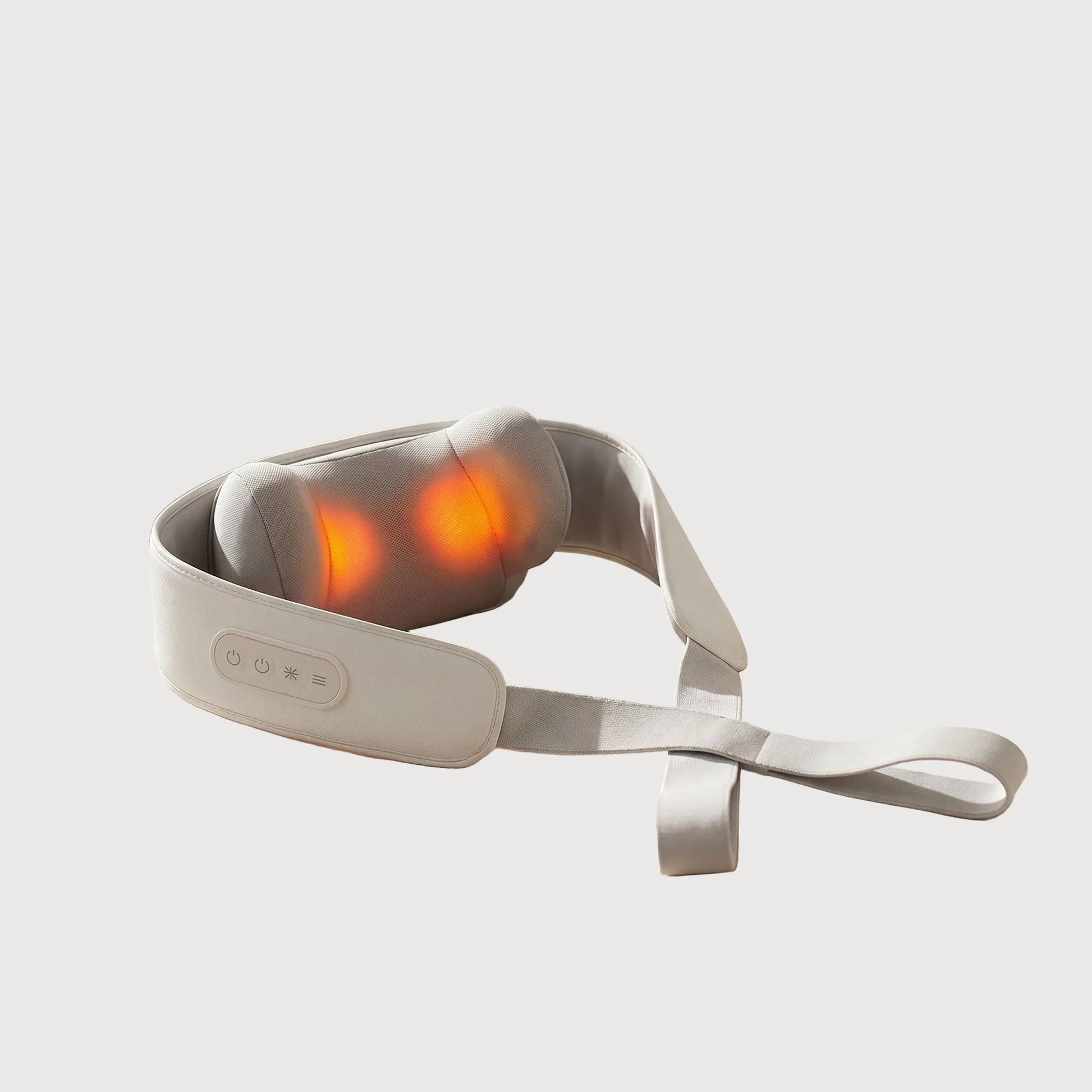 Massage belt with glowing red lights on a beige surface with towels and a plant in the background