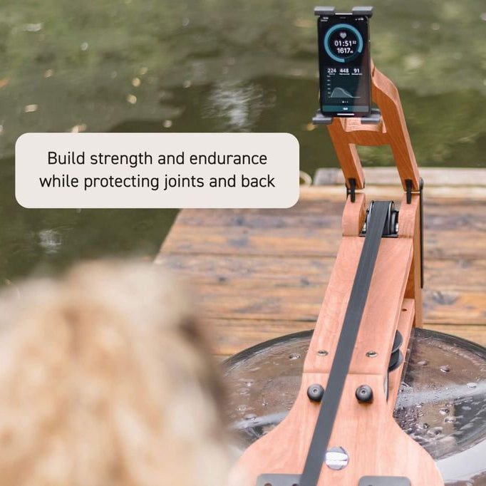 A wooden rowing machine with a digital display screen on a wooden dock next to water, with a text overlay that reads 'Build strength and endurance while protecting joints and back'.